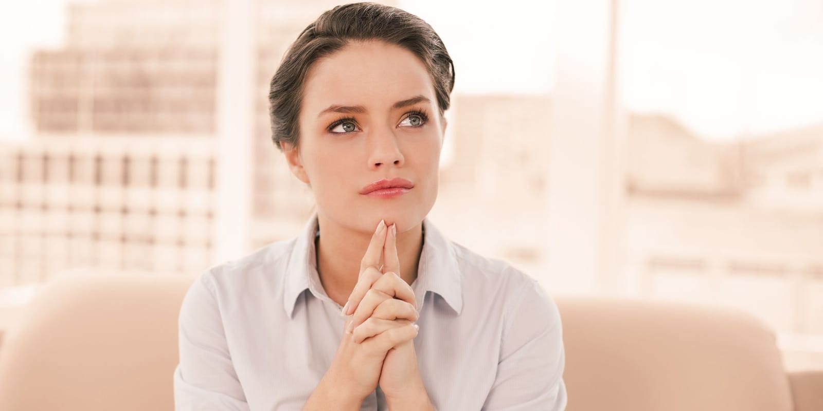 A thoughtful woman sitting with her hands clasped